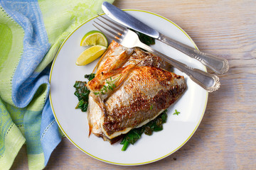 Dorado or dorada fish fillet with spinach, thyme and lime. View from above, top, horizontal