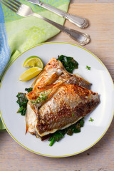 Dorado or dorada fish fillet with spinach, thyme and lime. View from above, top, vertical