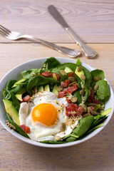 Fried egg with bacon, quinoa, avocado, spinach and pumpkin seeds for breakfast