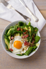 Fried egg with bacon, quinoa, avocado, spinach and pumpkin seeds for breakfast