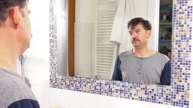 Man in front of mirror messing with hair trying to cover receding hairline