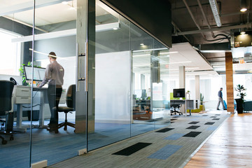 Man Working at Standing Desk in Glass-Walled Office