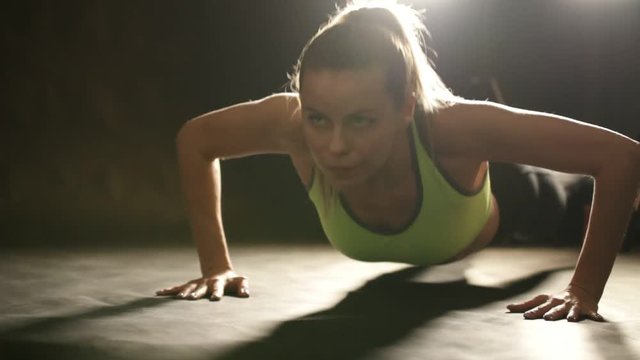 Attractive sportive woman in the fitness studio doing pushups exercises for arms