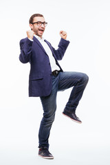 Excited elated happy young business man with beard in classic suit jumping and shouting over white background