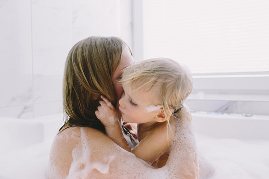 Mother and daughter embracing in bubble bath