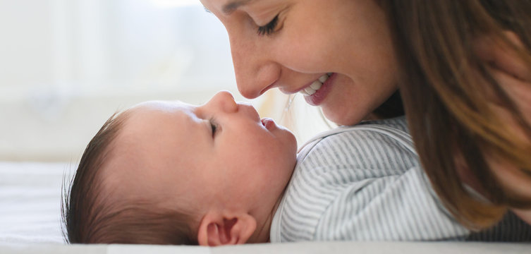 Mother Playing With Baby On Bed.