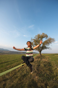 Young man sitting on slackline in lotus position