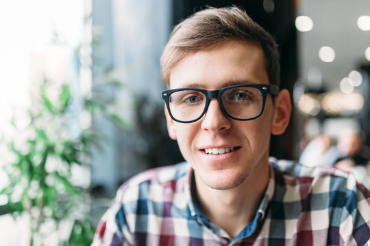 Portrait of a young man in glasses and a shirt with a positive mood and a wide smile