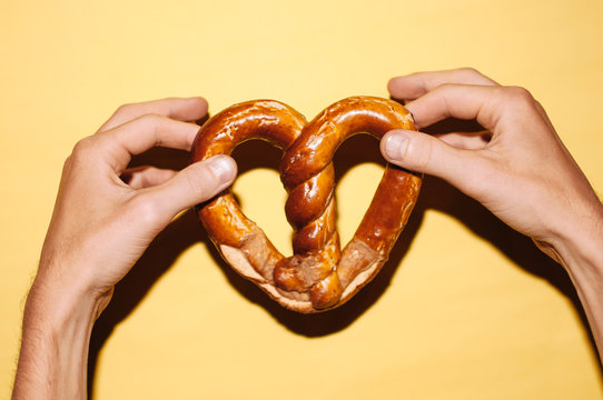 Hands holding heart-shaped pretzel
