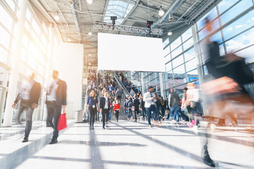 large crowd of anonymous blurred people in a modern hall