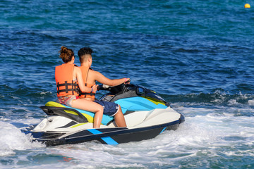 Young couple riding a jet ski in caribbean sea, wearing safety jackets. Riviera Maya, Mexico