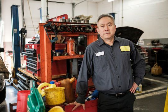 Asian car mechanic standing in his auto repair shop