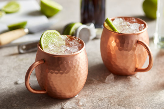 Cups of Moscow mule cocktail with sliced lime.
