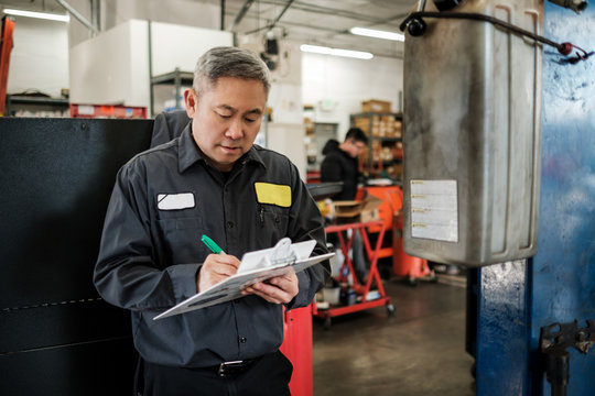 Asian car mechanic working in his auto repair shop