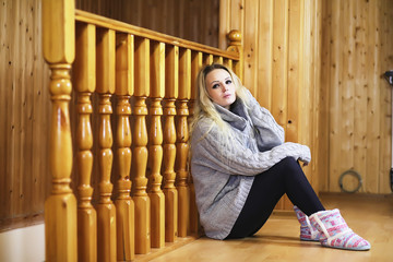 A young girl sits on a ladder in a sweater