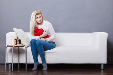 Woman feeling stomach cramps sitting on cofa