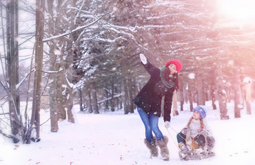 A winter fairy tale, a young mother and her daughter ride a sled