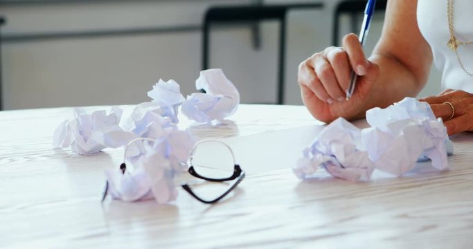 Mid section of executive writing on paper 