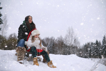 A winter fairy tale, a young mother and her daughter ride a sled