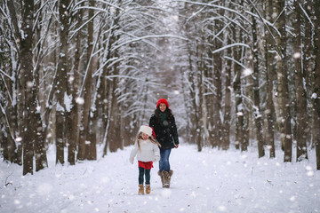 Fototapeta na wymiar A winter fairy tale, a young mother and her daughter ride a sled