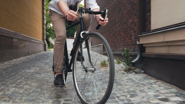 4k toned footage of young hipster man riding old black sport bicycle on narrow street