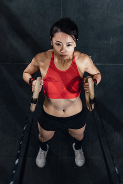 Young woman doing doing gym training with gymnastics rings