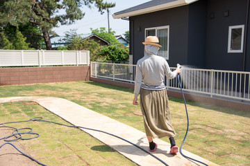 庭の水撒きをする女性