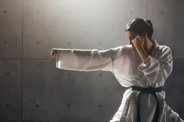 Fotobehang Martial arts Concept. Young woman in kimono practicing karate © a_medvedkov