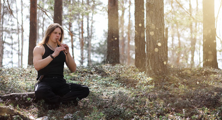 A musician with a tool in nature. A man is playing a flute in a 