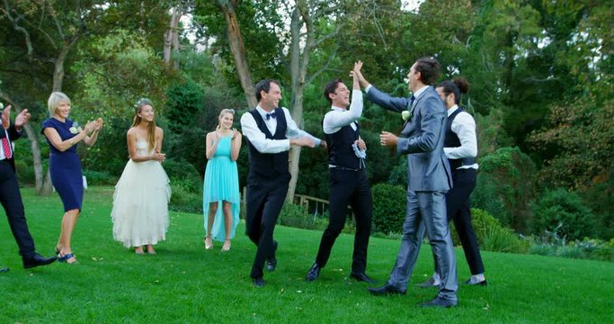 Groom And Groomsmen Enjoying Catching Garter Toss  