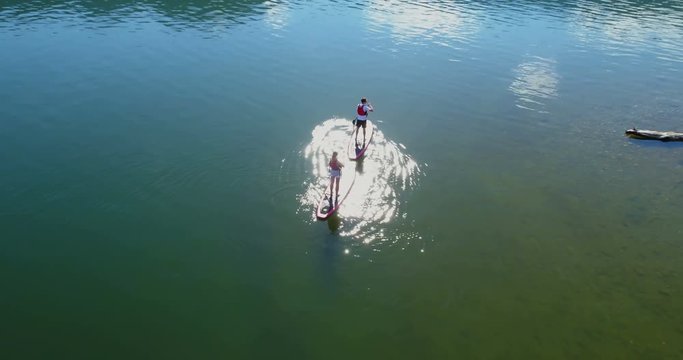 Couple on stand up paddle board oaring in river 