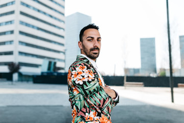Confident businessman in floral jacket with arms crossed.