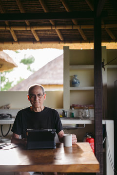 Mature man in his 60's working and traveling with tablet in trop