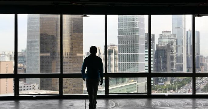 4k,businessman walking to the window & Overlooking the urban business building,skyscrapers,economic center.
