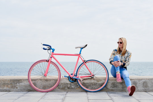 Woman with fixie on pier against seascape.