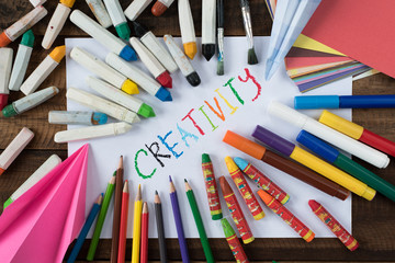 creativity concept - colorful paper, crayon, colorful pencil and paper with word CREATIVITY