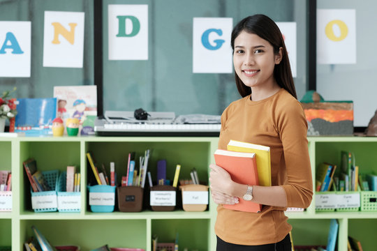 Young Asian Woman Holding Books Standing At Library Background, Education Concept