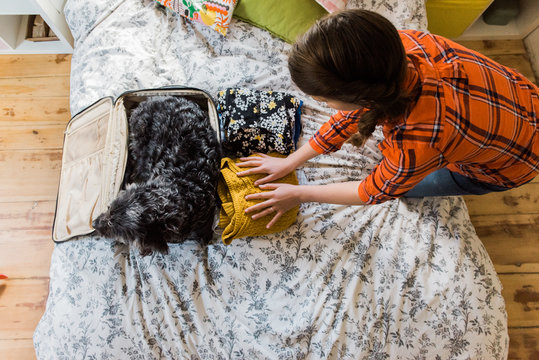 teen packing her suitcase with her dog