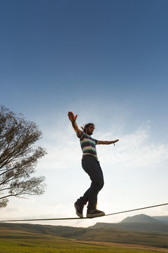 Young man taking steps on slackline outdoor in nature
