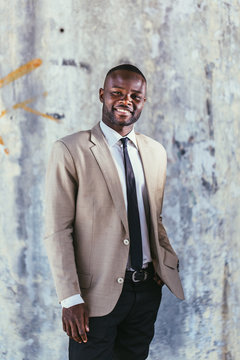 Black businessman standing in front a grey wall