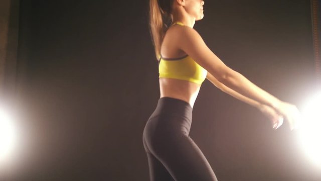 Flexible woman in studio doing squats exercises for buttocks