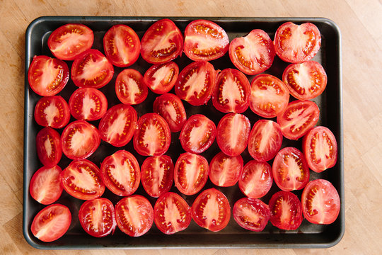 Sliced roma tomatoes on a baking tray