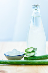 Fresh aloe vera leaves with aloe vera juice in bottle on wooden