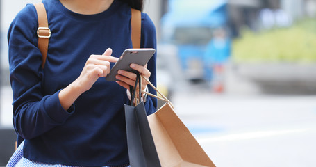 Obraz premium Woman holding paper bag and use of mobile phone