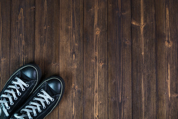 Black sneakers on dark wooden background with copy space. Top view. Hipster style. travel concept.