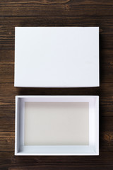 Fototapeta premium Empty white gift box or tray for mock up on dark wooden table with copy space.