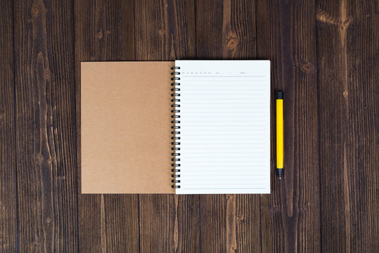 Notebook and empty white paper with pen on wood table top view with copy space