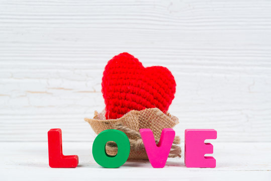 Valentine card with Love text and red knitting heart on white wooden background and copy space for add text and picture, love and valentine day concept.