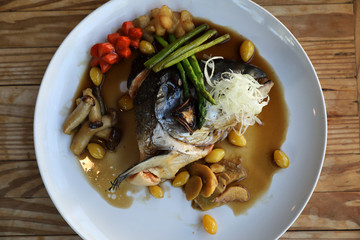 Salmon head tari yaki sauce with fresh vegetables on wood background