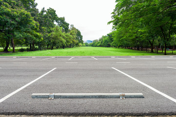 Obraz premium Empty parking lot against green lawn in city park